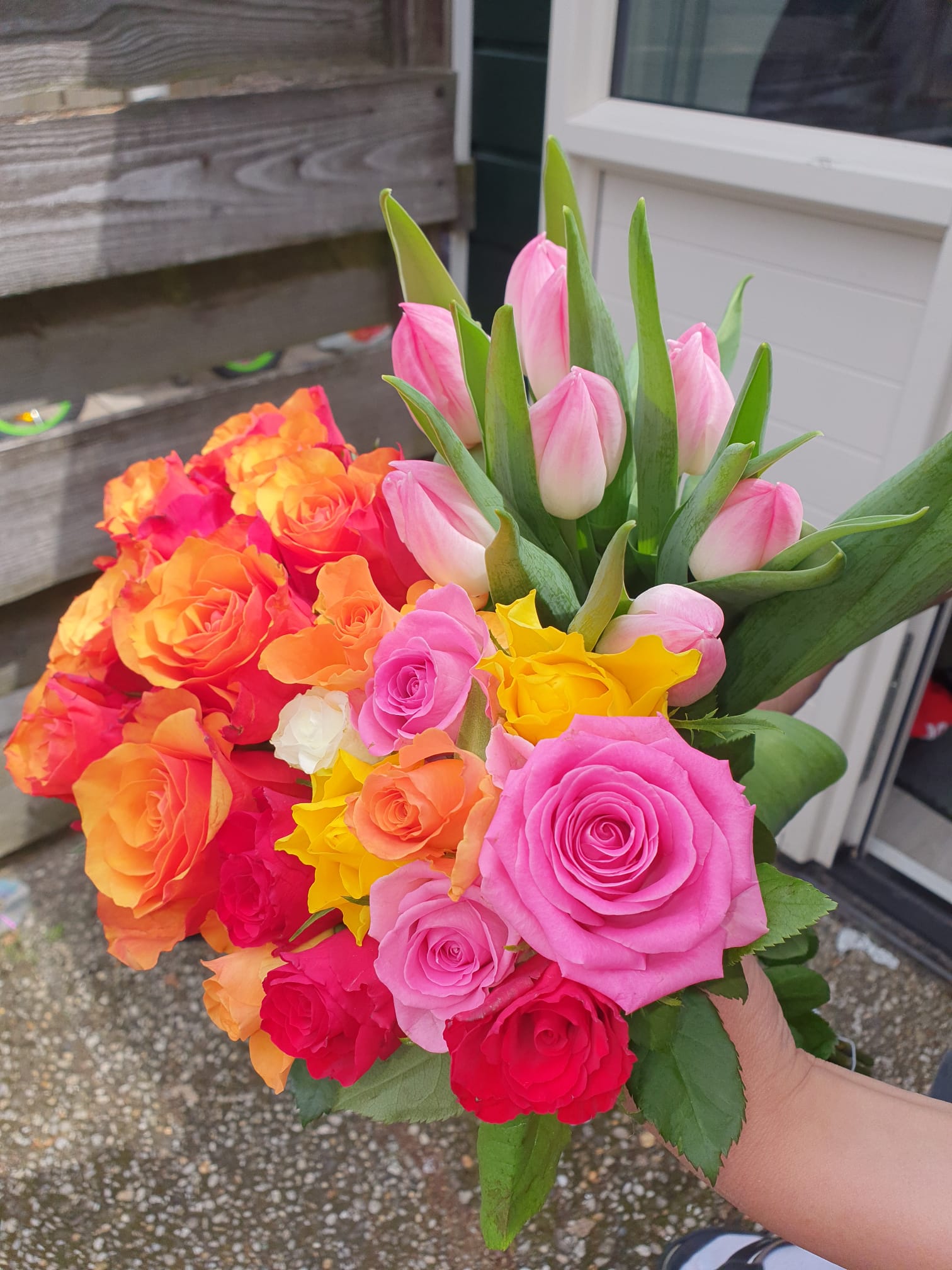 A bouquet of roses and tulips held by the door